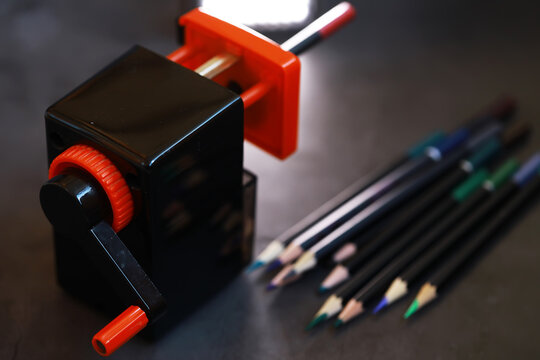 Manual Pencil Sharpener and Colored Pencils on Dark Surface for Creative Artistic Work