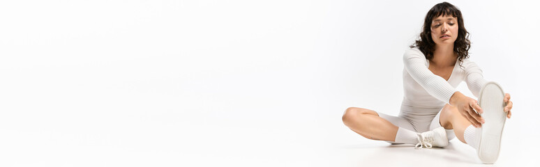 Young beautiful woman stretching in stylish athletic wear, focusing on fitness and wellness