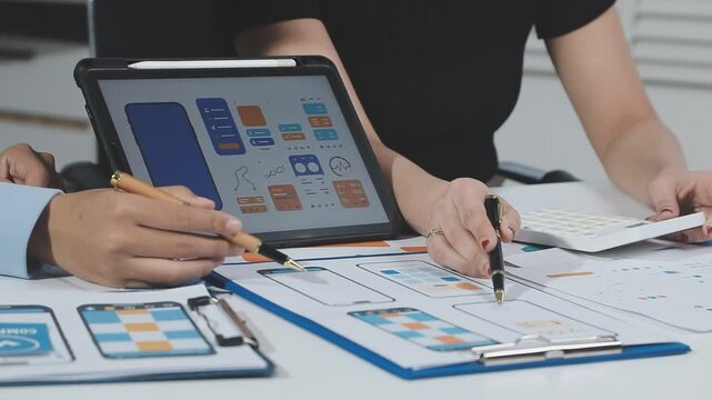 Two UX UI designers brainstorming mobile app wireframes in a modern startup office, showcasing creative teamwork, digital design