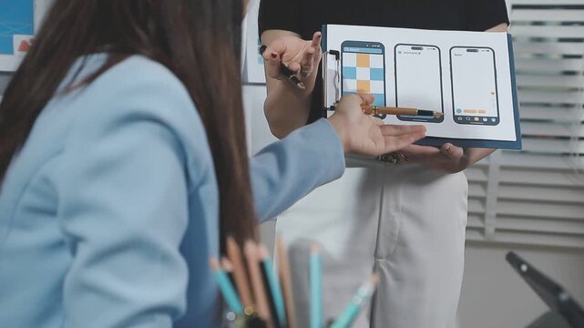 Two UX UI designers brainstorming mobile app wireframes in a modern startup office, showcasing creative teamwork, digital design