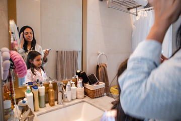 A woman is brushing her teeth in front of a mirror