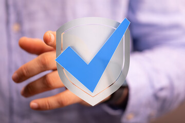 Concept of approval, security and protection represented by a hand holding a shield with a check...