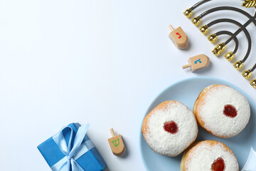 A festive Hanukkah composition featuring a menorah, dreidel set, and a gift on a white background