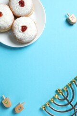 Festive Hanukkah vertical scene with dreidels, golden menorah,  jelly donut arranged on a light...