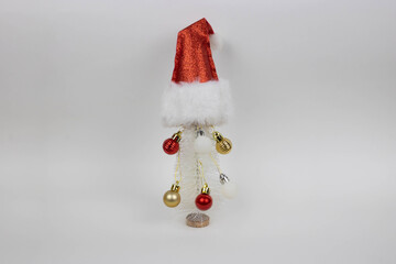 A small artificial white Christmas tree with ball ornaments and a red Santa Claus hat.