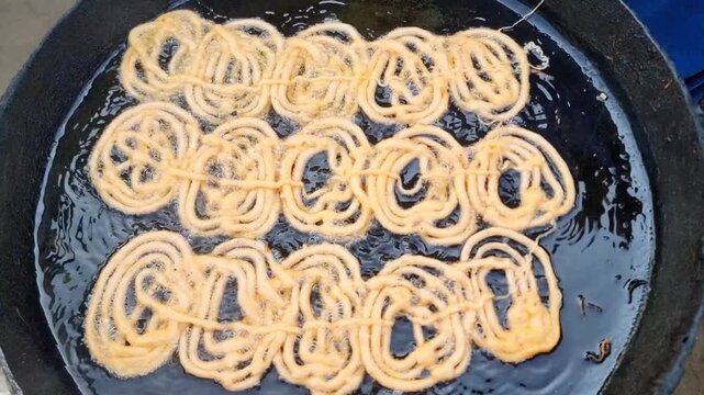 Jalebi is a Pakistani dessert. Sweet with sugar syrup fried in oil or ghee. Fresh batch of Jalebi. Crispy Jalebi.(traditional Pakistani sweet dessert). Pakistani jalebis arranged for sale. 4K Footage.