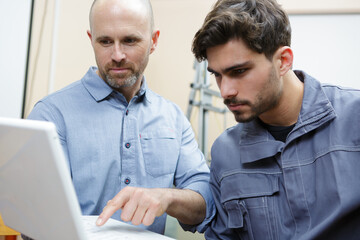 a portrait of two men holding the laptop