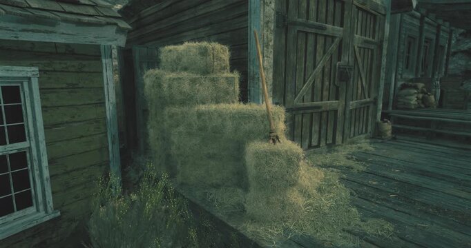 Bales of hay are stacked against a rustic wooden structure surrounded by overgrown grass. The setting is peaceful, showcasing rural life during the evening hours.