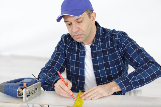 worker working with a measuring tape and pencil in plank