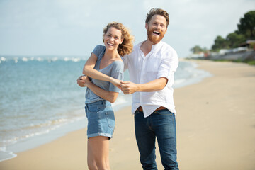 cheerful couple dancing on the beach