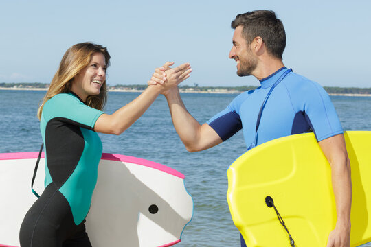 happy couple doing high five after doing bodyboard - Powered by Adobe