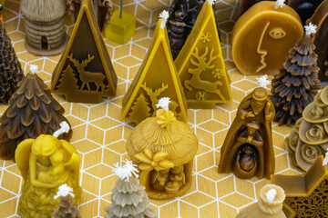 Candles in various shapes arranged on a patterned surface showcasing winter and festive decorations in a cozy market setting