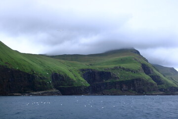 Fototapeta premium view to Mykines Island showcasing towering cliffs surrounded by the expansive North Atlantic Ocean, Faroe Islands, Denmark