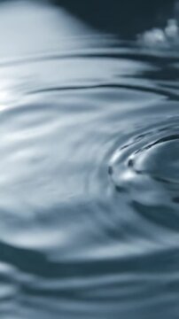 Extremely detailed slow motion close up of subtle concentric ripples spreading across a liquid surface signifying low frequency vibration texture, meditation, impact