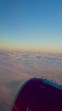 Vertical video from the window of an airplane. Dawn from an airplane. Travel and tourism, view from the passenger window of a modern airplane, vertical video.