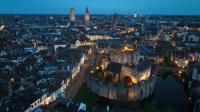 evening orbiting drone shot of Ghent medieval fortress in Belgium with night illumination, unesco world heritage site in Belgium, travel in the Flemish region