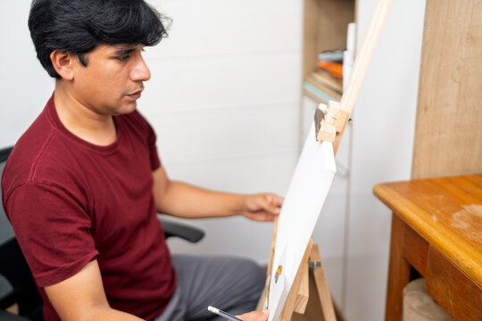 Male artist drawing bird artwork on canvas