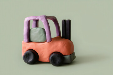 Clay forklift model with orange body and purple frame isolated on green background, playful and creative handmade toy