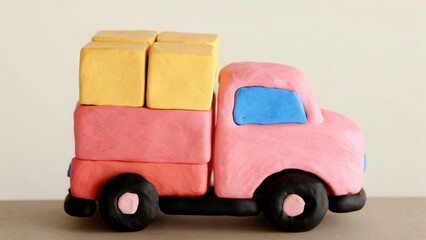Clay model of pink cargo truck with yellow boxes and black wheels on neutral background, playful and colorful design