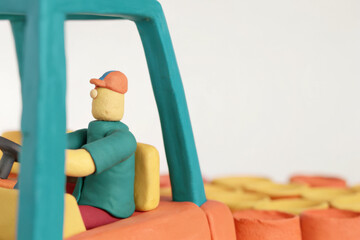 Clay figure driving forklift in warehouse with colorful boxes, showing detailed craftsmanship and playful design