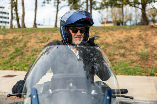 Senior man riding motorcycle using mobile phone - Powered by Adobe