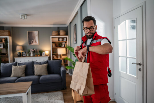 Delivery man checking time delivering food at home - Powered by Adobe