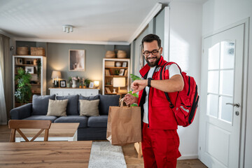 Smiling courier checking watch ready for food delivery