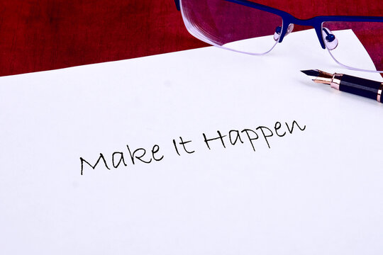 A motivational statement encouraging action is handwritten on a clean sheet of paper. Reflections from reading glasses and a fountain pen add a touch of creativity to the workspace