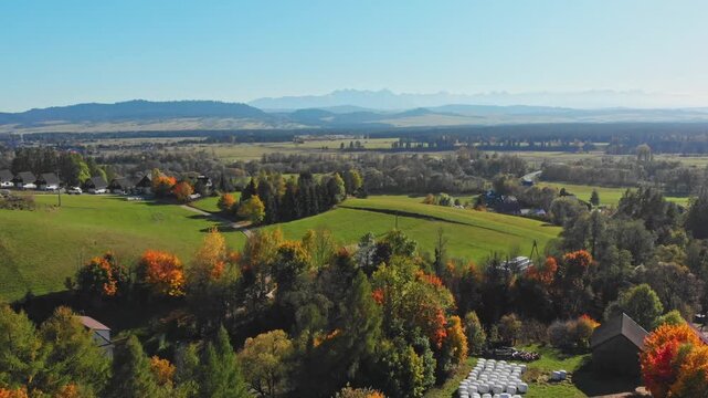 Aerial footage showing open fields, autumn trees and a distant panorama of the Tatra Mountains near Szlembark in the Podhale region of southern Poland.