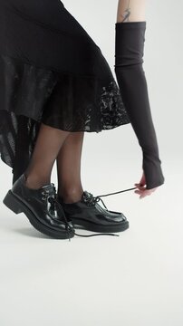 Woman untying shoelaces and taking off black leather shoes