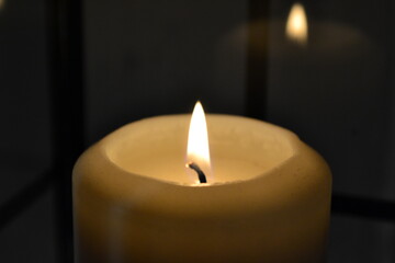 Lit decorative candles creating a warm cozy ambiance. Soft shadows, elegant still life scene, home interior mood.