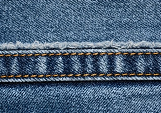 Blue denim fabric close-up showing folded hem and detailed stitching for textile background