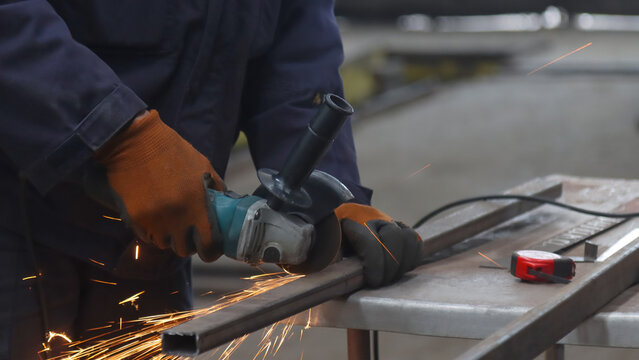 Industrial metal cutting by a worker with a halo of bright sparks from an angle grinder