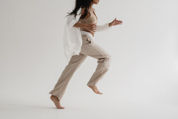 Lifestyle running and jumping blur motion with woman in neutral clothing on white background.