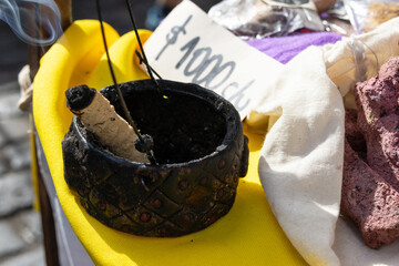 A piece of incense is inside a rustic incense holder; next to it is a price tag