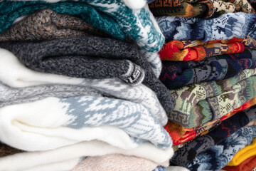 various pieces of clothing made of wool in different prints, folded into stacks