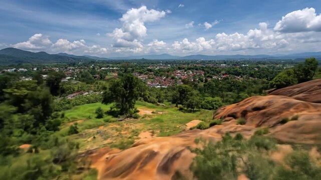 Scenic aerial landscape view with rolling hills and distant town under cloudy sky