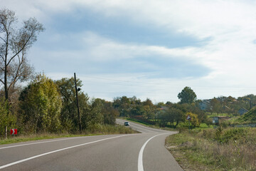 Winding countryside road meanders through vibrant autumn landscape under a bright blue sky
