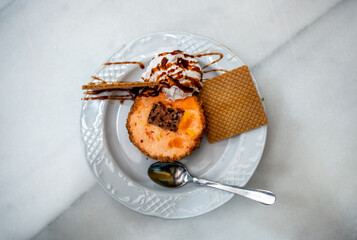 Artisan orange ice cream served with crispy cookies and whipped cream, sprinkled with caramel sauce in an Andalusian restaurant in Cordoba, Spain