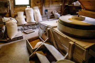Inside the old wooden flour grinding mill. Interior of retro wooden watermill with old equipment for grinding or milling grain into flour