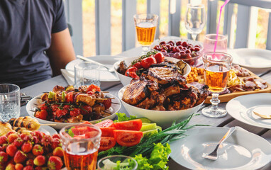 Vegetables and meat are grilled on the table with wine and people. Selective focus.