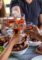 Vegetables and meat are grilled on the table with wine and people. Selective focus.