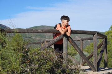 adventure and outdoor activities. Preteen boy leaning over a viewpoint while hiking