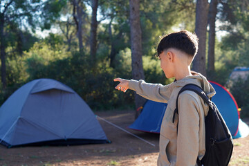 adventure and outdoor activities. Preteen boy pointing at the tent set up at the campsite.