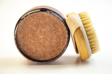 Round container filled with brown sugar scrub alongside a natural bristle brush, emphasizing beauty and skincare essentials for a rejuvenating self-care experience