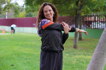 sports and outdoor activities. woman with curly hair wearing a tracksuit doing stretches in the park