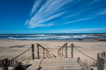 Boardwalk over dunes of Canide Beach on northern coast of Portugal in Vila Nova de Gaia under dramatic autumn cloudscape.