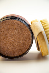 Round container of brown sugar body scrub with a natural bristle brush, emphasizing beauty and skincare essentials for effective self-care and relaxation