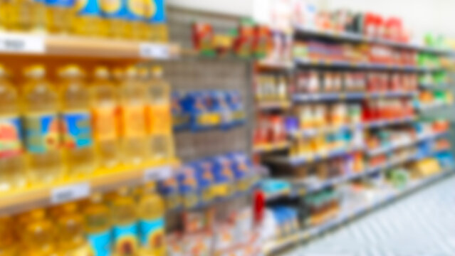 Blur supermarket background. Defocused shelves with products. Grocery store. Retail industry. Discount. Inflation concept. Aisle. CPG. Rack. Tariff reprieve. Price hikes. Bottles of sunflower oil.