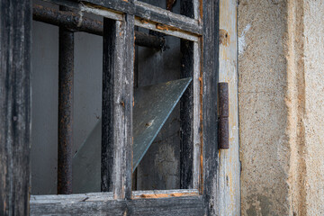 Broken Wooden Window Frame with Rusty Bars and Weathered Glass in Abandoned Building Detail